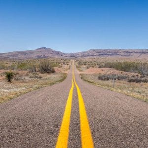 Long straight two-lane road running through the Texas backcountry near Big Bend National Park