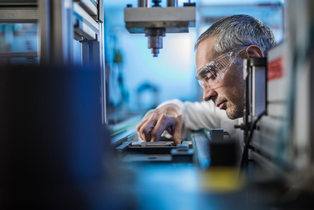 Quality control worker analyzing a component on a manufacturing machine