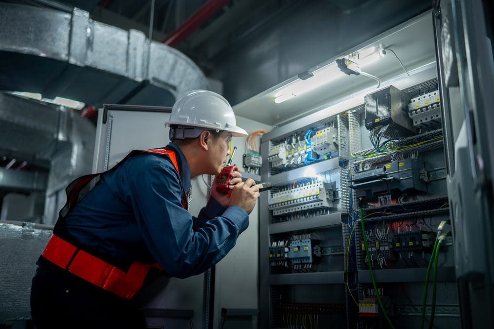 Industrial technicians working at a well-organized electrical control cabinet panel