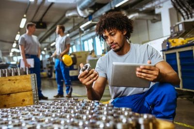 Worker checking metal parts against the paperwork