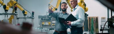 Engineers planning robotic automation on a tablet in a factory