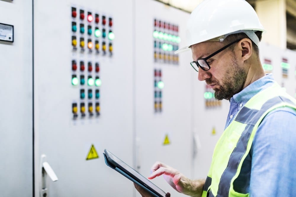Electrical engineer checking power in a control room using a tablet