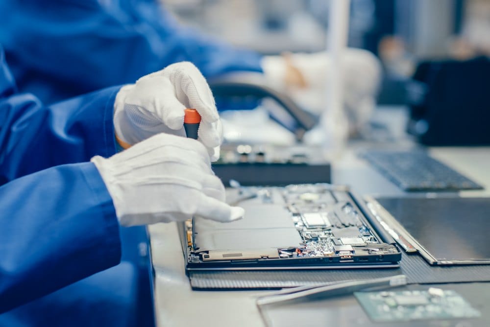 Electronics factory worker assembling a motherboard with a screwdriver