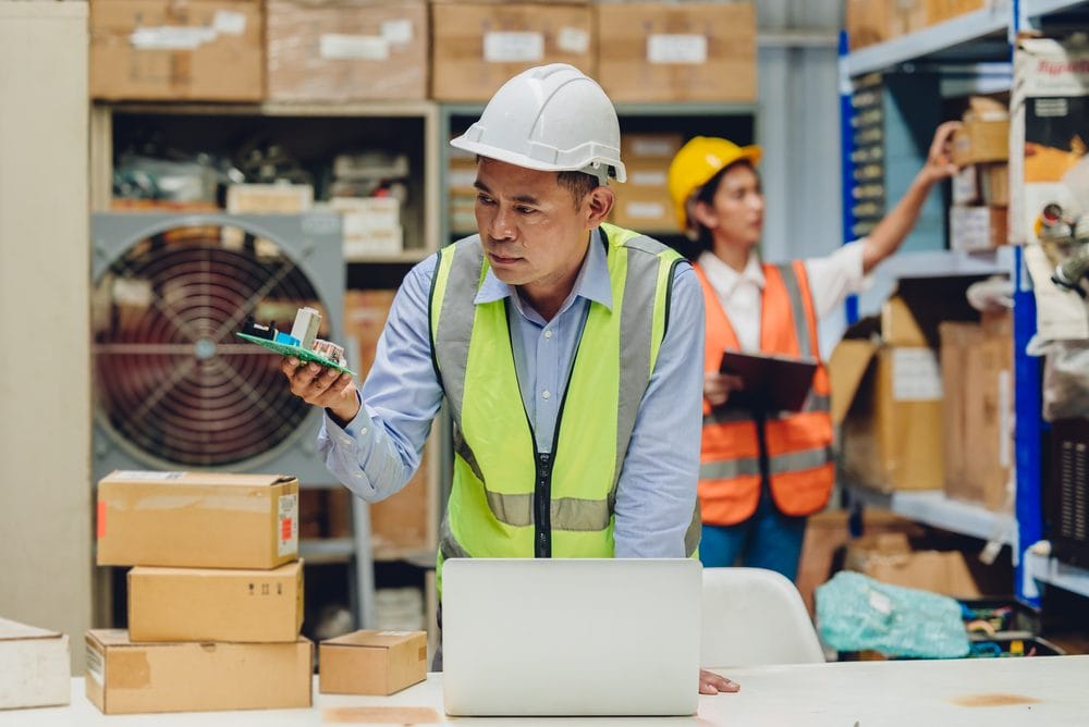 Senior engineer checking a spare part against its specification in a warehouse