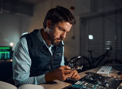 Technician working on a circuit board at a repair bench