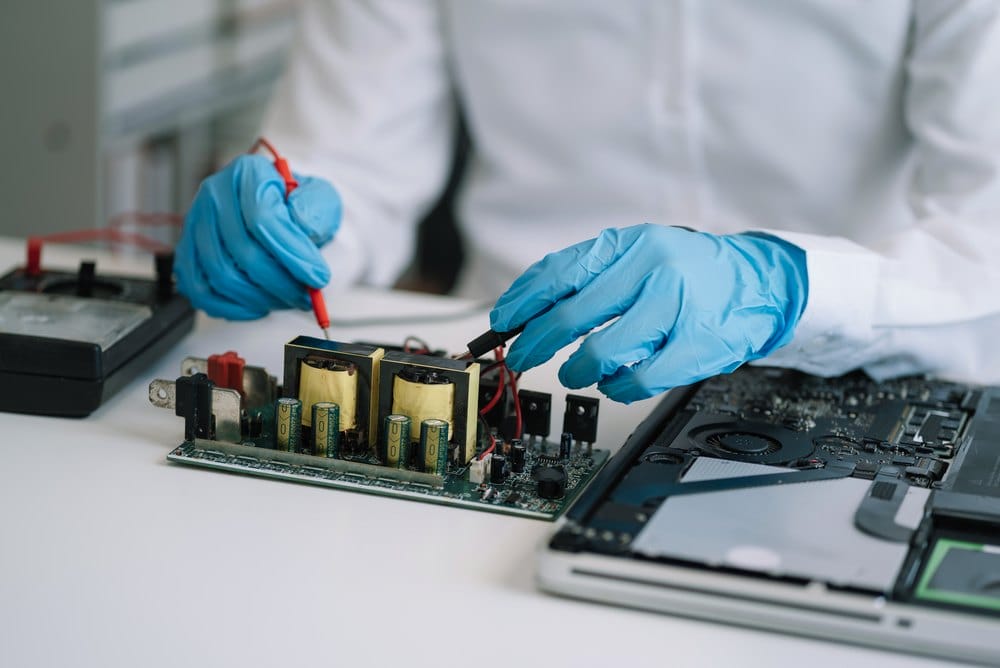 Technician hands examining an electronic device during assessment