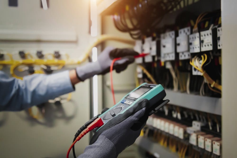 Service engineer checking voltage with a multimeter at a distribution board