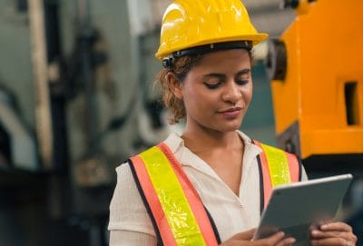 Engineering supervisor checking machine performance on a tablet in a heavy industry factory