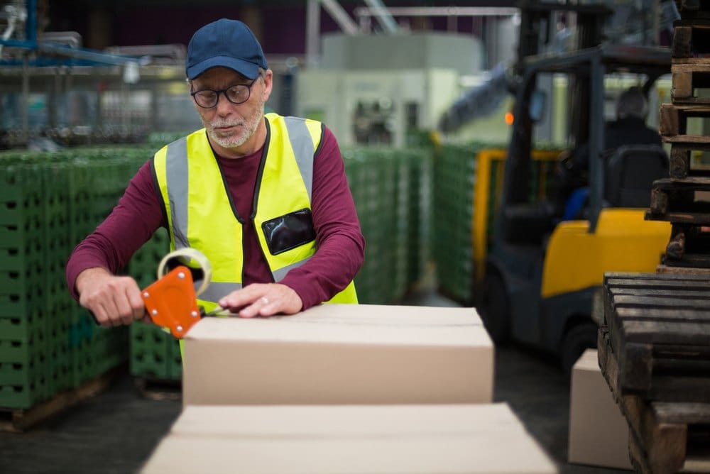 Worker sealing a cardboard shipping box with tape
