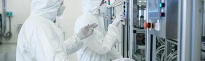 Technicians in sterile protective clothing working on semiconductor manufacturing equipment