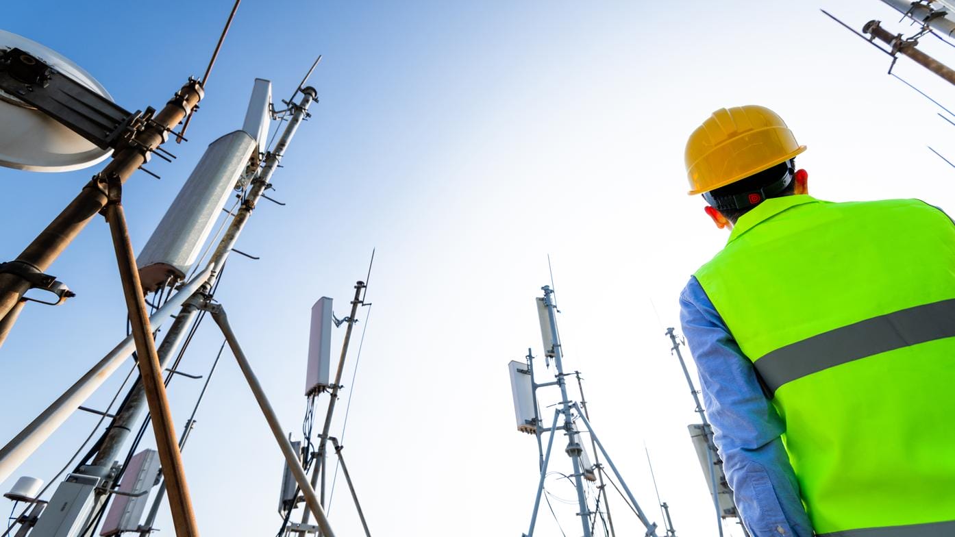 Technician looking up at a communications tower